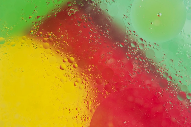 Free Photo transparent water drop over the red; yellow and green backdrop