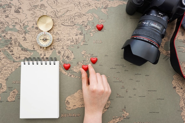 Free photo travel background with hand placing hearts on a world map