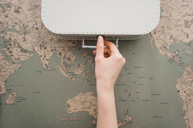 Free photo travel background with hand next to a suitcase