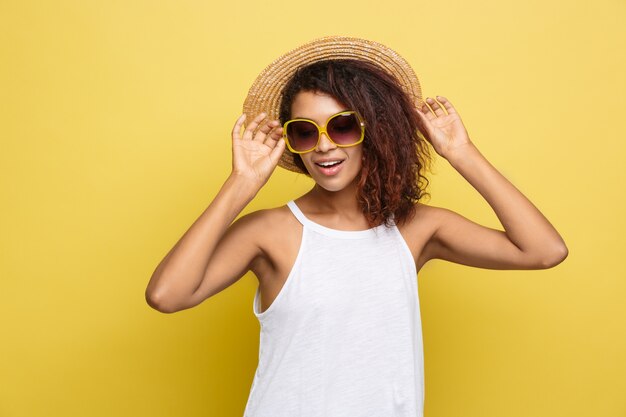 Travel concept - Close up Portrait young beautiful attractive African American woman with trendy hat smiling and joyful expression. Yellow Pastel studio Background. Copy space.