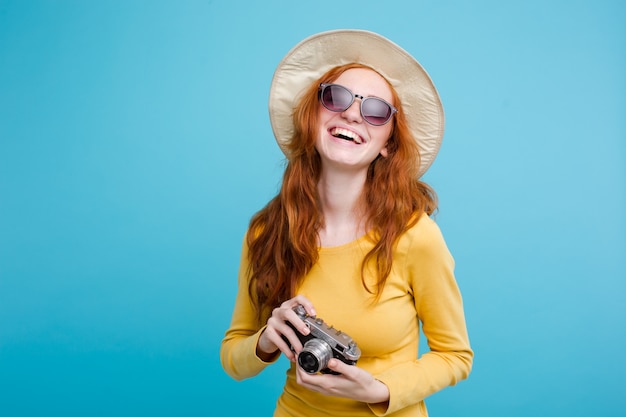 Travel concept - Close up Portrait young beautiful attractive redhair girl wtih trendy hat and sunglass smiling. Blue Pastel Background. Copy space.