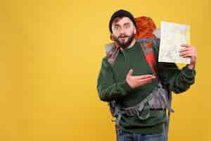 Free photo travel concept with wondering young guy with packpack and holding map on yellow