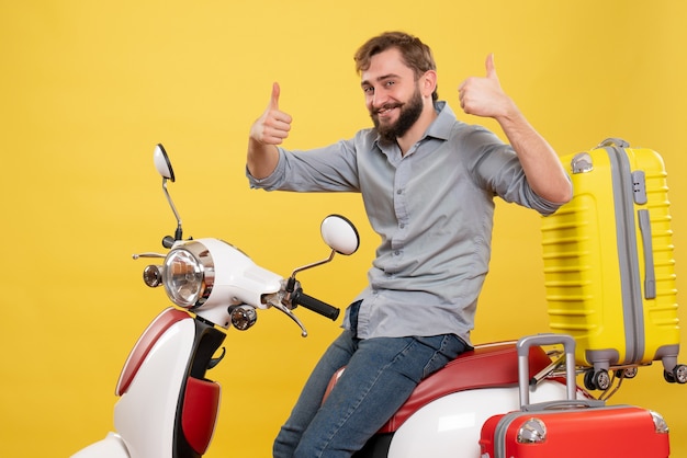 Free photo travel concept with young confident bearded man sitting on motocycle making ok gesture on it on yellow