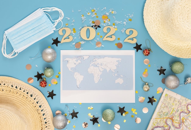 Free Photo travel flat lay composition with world map and numbers 2022 on blue background.