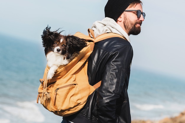 Free photo travel hipster man with dog in backpack