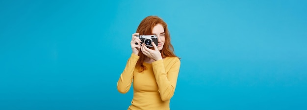 Free photo travel and people concept headshot portrait of happy ginger red hair girl ready to travel with vintage camera in happy expression pastel blue background copy space