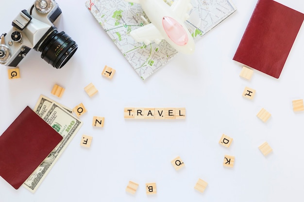 Free photo travel wooden blocks; camera; map; banknotes; passport and airplane on white background