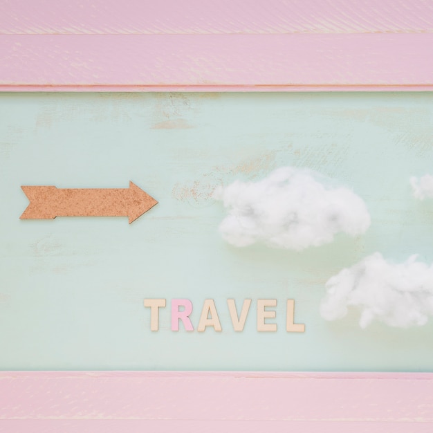 Free photo travel word with clouds and arrow against painted wall