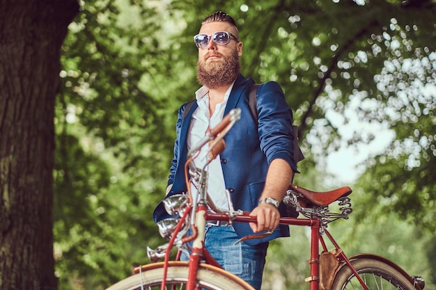 A traveler dressed in casual clothes and sunglasses with a backpack, relaxing in a city park after riding on a retro bicycle.