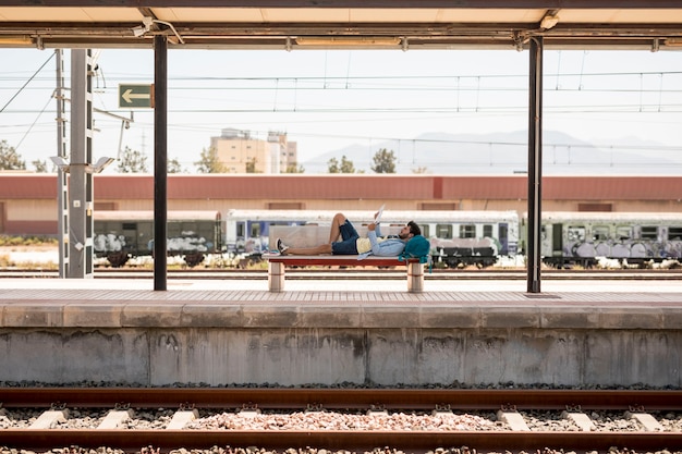 Free photo traveler lying on the bench waiting for train