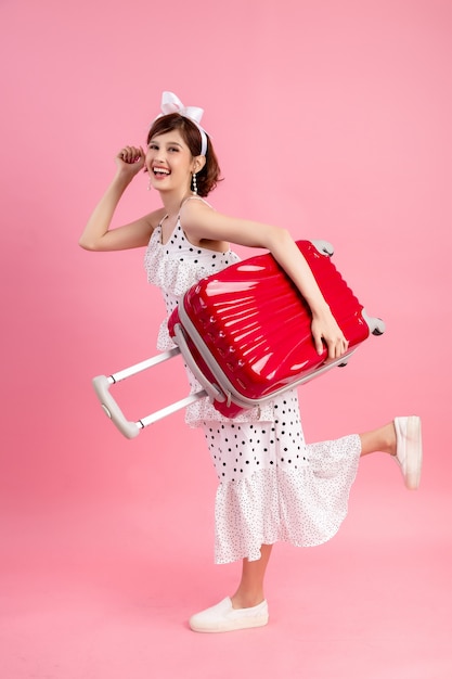 Traveler tourist woman in summer casual clothes with travel suitcase isolated on pink