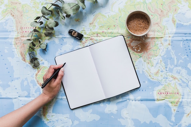 A traveler writing on blank notebook with car toy, coffee over the map