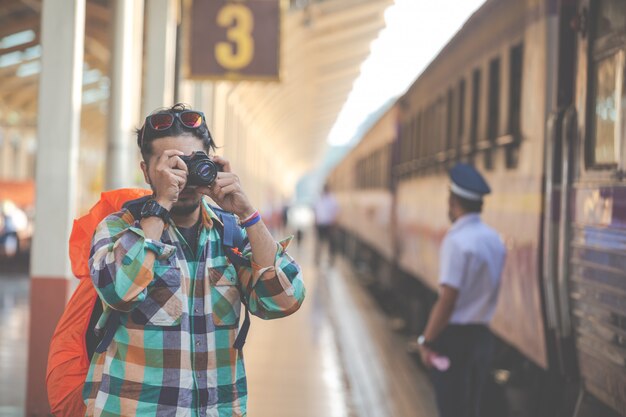 Travelers take pictures of couples while waiting for trains.