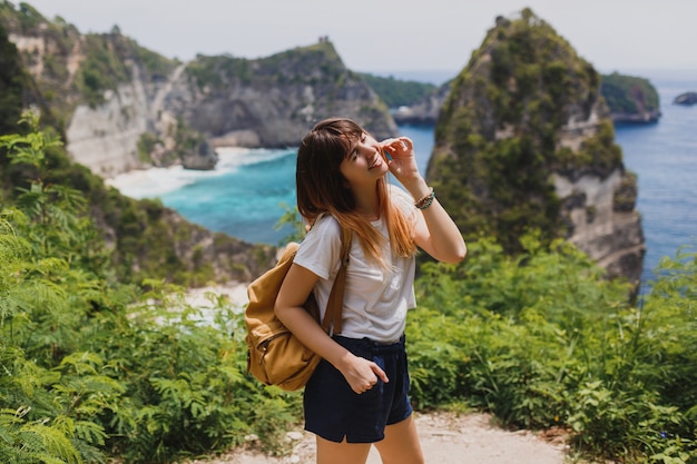 Free photo traveling and adventure concept. happy woman with back pack traveling in indonesia on nusa penida island.