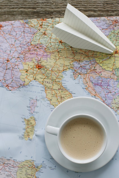 Free photo traveling map, paper plane and coffee cup