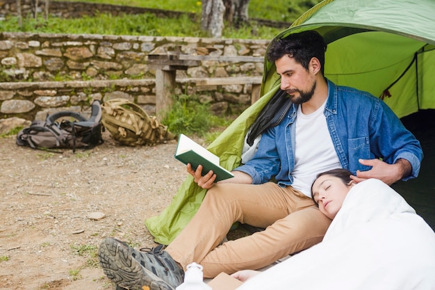 Free photo traveller reading book near sleeping woman