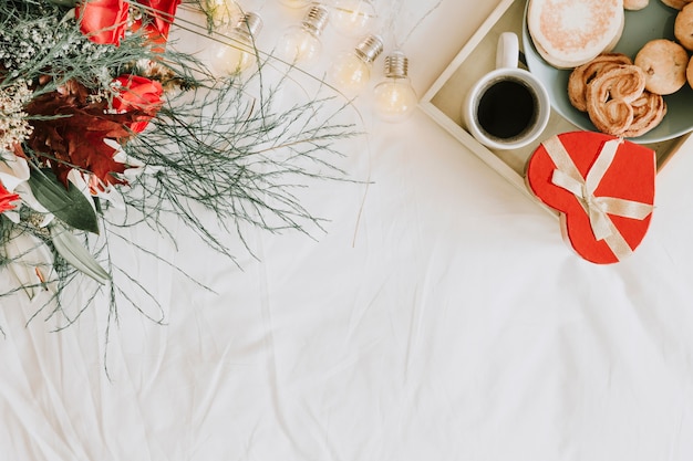 Tray with breakfast and present near bouquet