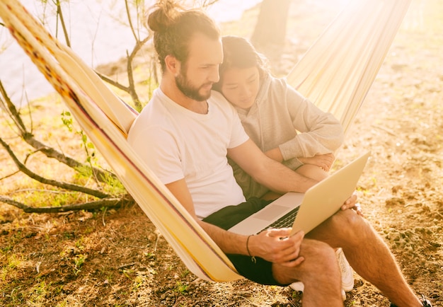 Free photo trendy couple resting together in hammock outdoors