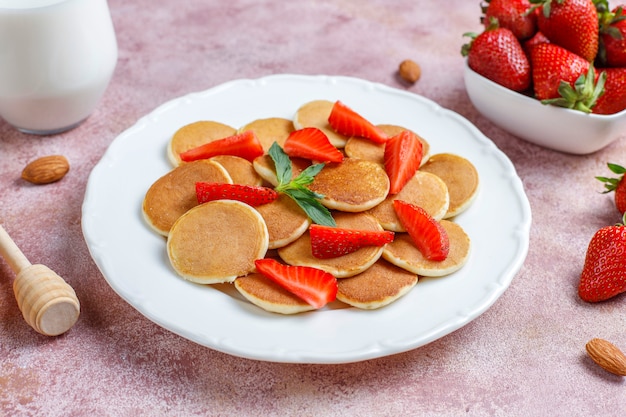 Free photo trendy food - mini pancake cereal. heap of cereal pancakes with berries and nuts.