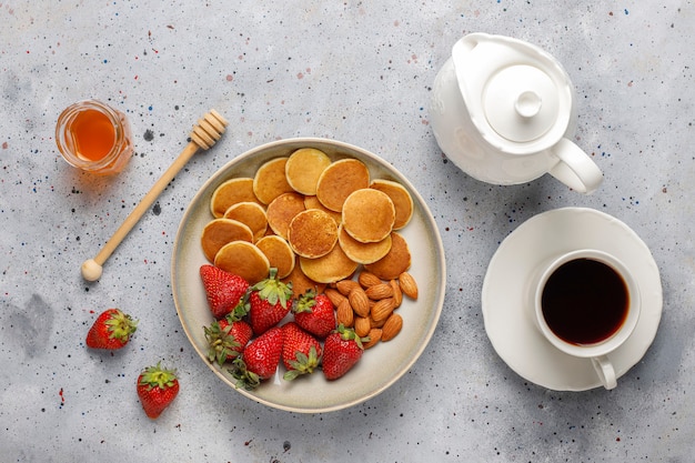 Free photo trendy food - mini pancake cereal. heap of cereal pancakes with berries and nuts.