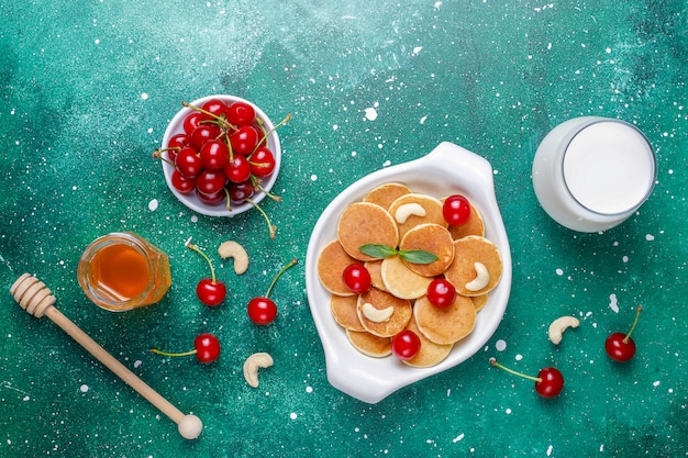 Trendy food - mini pancake cereal. Heap of cereal pancakes with berries and nuts.