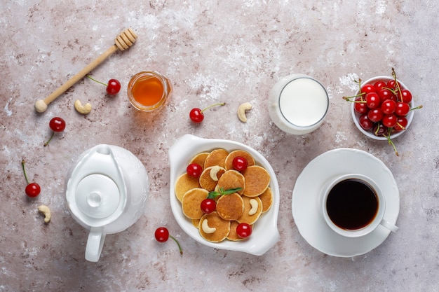 Free photo trendy food - mini pancake cereal. heap of cereal pancakes with berries and nuts.