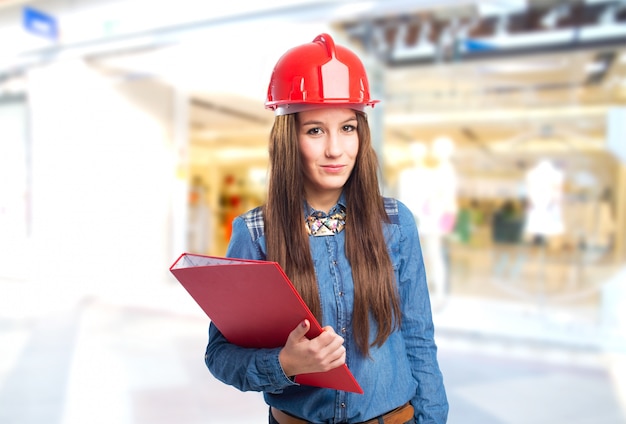 Trendy young woman holding a red folder and wearing a helmet