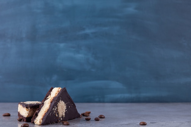 Triangle shape slices piece of dark chocolate cake with coffee beans . 