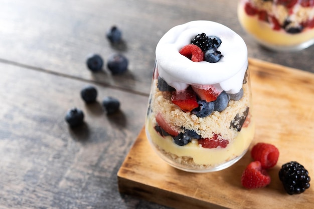 Free photo trifle dessert with berries and cream on wooden table