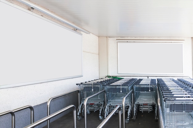 Trolleys luggage in shopping center with blank billboards for advertisement