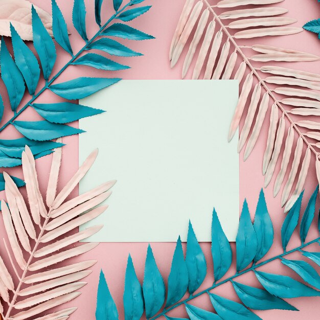 Tropical palm leaves with white paper blank on pink background