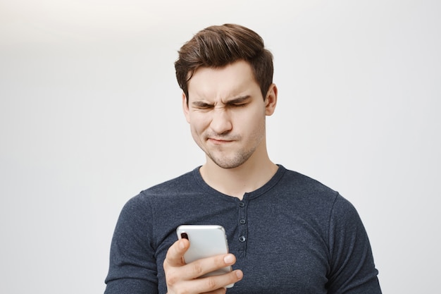 Free Photo troubled confused guy looking at mobile phone message