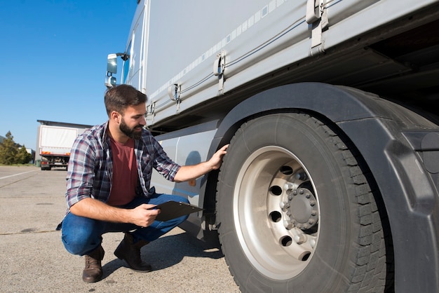 Free Photo truck driver inspecting tires and checking depth of tire tread for safe ride