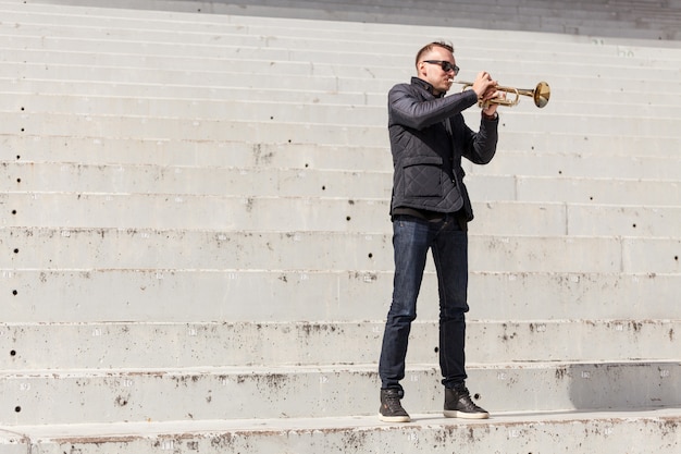 Free photo trumpet player standing on stairs