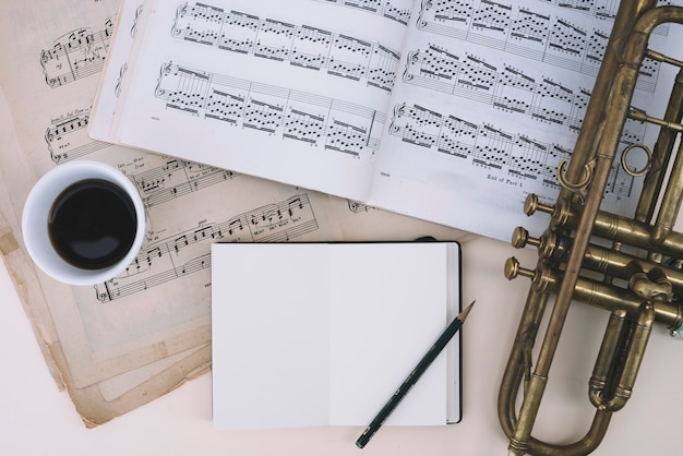 Free photo trumpet and sheet music near drink and notepad