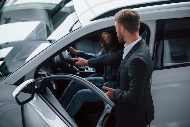 Free Photo try how it feels. female customer and modern stylish bearded businessman in the automobile saloon