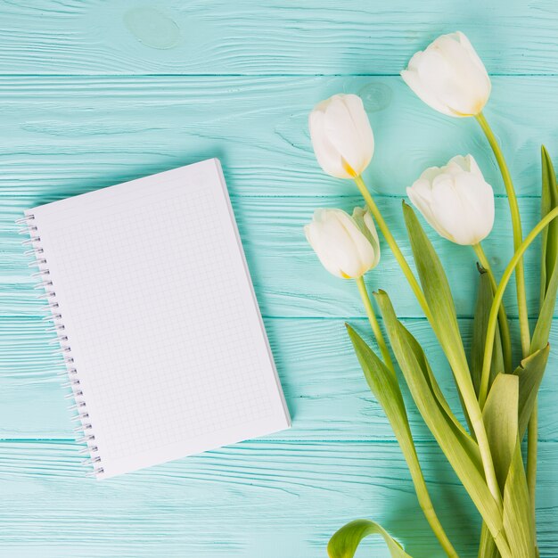 Tulip flowers with blank notebook on wooden table