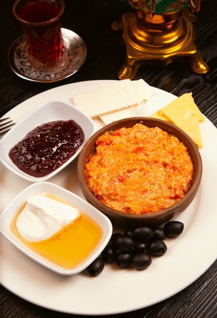 Turkish breakfast, menemen with cream, honey, black olives, jam, cheese variations and glass of tea. 