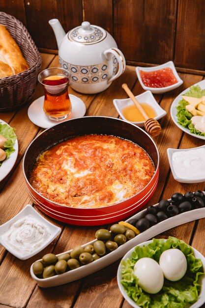 Turkish breakfast setup with egg and tomato dish sausages olives eggs and tea