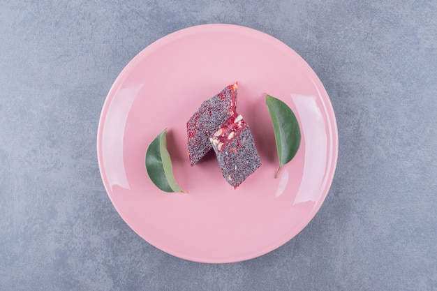 Turkish delight rahat lokum with pistachios on pink plate.