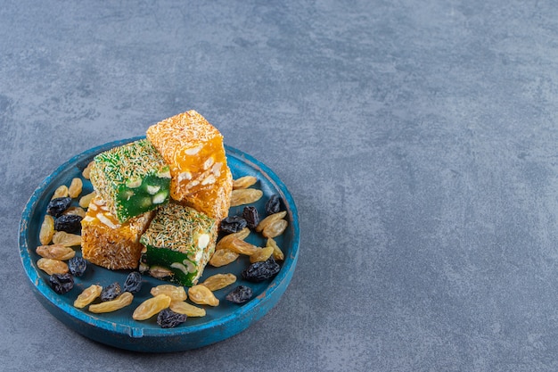 Free Photo turkish delights and raisins on a wooden plate, on the marble background.