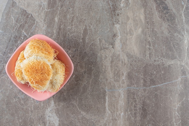 Free photo turkish dessert kadayif in a bowl on marble.