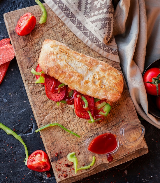 Free Photo turkish sucuk ekmek sandwich in baguette on a wooden table with tablecloth and vegetables around