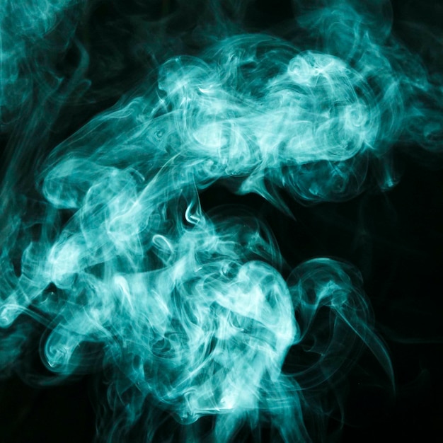 Turquoise smoke clouds spread out wide against black background