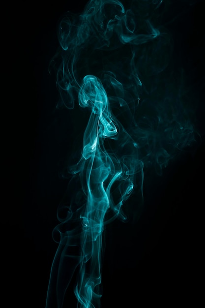 Turquoise smoke spread out wide against dark black background