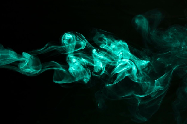 Free photo turquoise smoke trail on black background