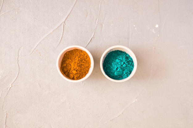 Free photo turquoise and yellow holi color powder in the two bowl on concrete backdrop