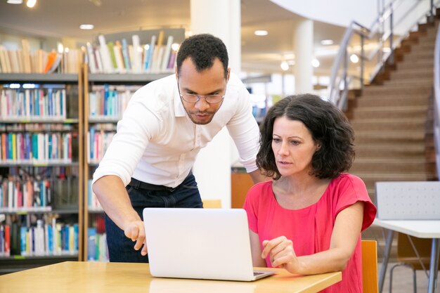 Tutor explaining research specific to student in library