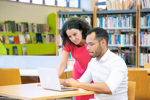 Tutor helping student with research in library