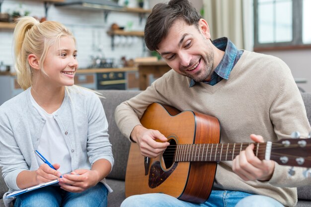 Tutor showing his young student how to play the guitar